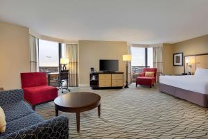 a hotel room with a bed and a couch and chairs at Hilton Rosemont Chicago O'Hare in Rosemont