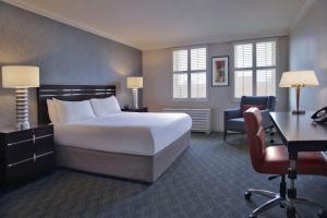 ein Hotelzimmer mit einem großen Bett, einem Schreibtisch und einem Stuhl in der Unterkunft Hilton Orrington/Evanston in Evanston