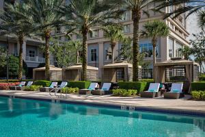 a hotel swimming pool with lounge chairs and palm trees at Waldorf Astoria Orlando in Orlando