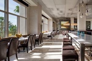 a dining room with tables and chairs and windows at Signia by Hilton Orlando Bonnet Creek in Orlando