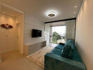 sala de estar con sofá azul y TV en Apartamento em Bombas, en Bombinhas