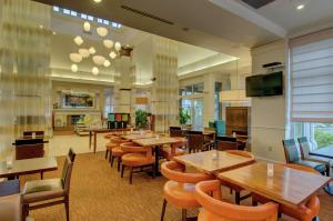 a restaurant with tables and chairs and a flat screen tv at Hilton Garden Inn Norwalk in Norwalk