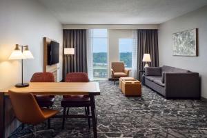 Embassy Suites by Hilton Hampton Convention Center في هامبتون: غرفة معيشة مع أريكة وطاولة في غرفة الفندق