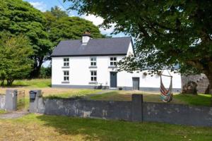 ein weißes Haus mit einer Flagge davor in der Unterkunft Cosy Cottage in Galway in Creggs