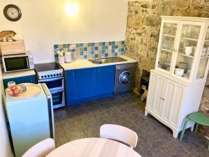een keuken met blauwe kasten en een wastafel bij Cosy Cottage in Galway in Creggs