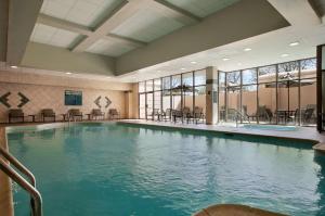 a large swimming pool with tables and chairs in a building at Embassy Suites by Hilton Philadelphia Airport in Philadelphia