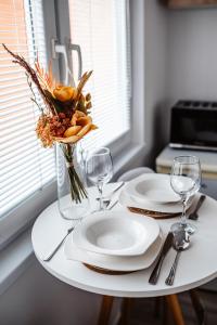 a table with plates and glasses and a vase with flowers at Apartmán Nová Nemocnica 10min. pešo do Centra in Košice