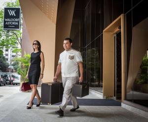 un hombre y una mujer caminando por una calle con maletas en Waldorf Astoria Panama, en Panamá