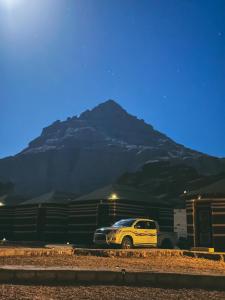 a yellow truck parked in front of a mountain at Full moon camp in Disah