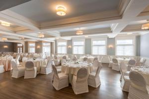 un salón de banquetes con mesas y sillas blancas en The Strathallan - a DoubleTree by Hilton en Rochester