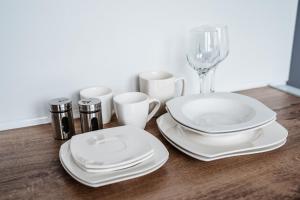 a table with white plates and cups and a wine glass at Apartmán Nová Nemocnica 10min. pešo do Centra in Košice