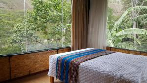 a bedroom with a bed and a large window at Araplay Lodge in Santa Teresa