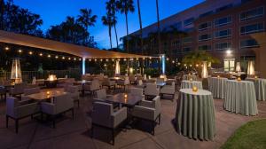 a restaurant with white tables and chairs and a building at DoubleTree by Hilton San Diego Del Mar in San Diego