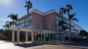 a brown building with palm trees in front of it at DoubleTree by Hilton San Diego Del Mar in San Diego
