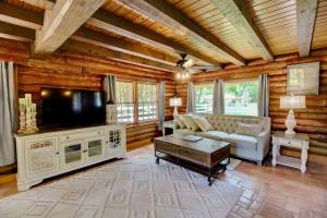 ein Wohnzimmer mit einem TV, einem Sofa und einem Tisch in der Unterkunft Unplug and Recharge: Bayou Log Cabin Retreat in Dickinson