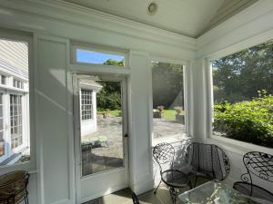 a screened in porch with chairs and windows at 5 Plus Bedroom Over Sized Colonial in Very Private Setting in Pound Ridge
