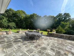 a patio with a table and chairs in a yard at 5 Plus Bedroom Over Sized Colonial in Very Private Setting in Pound Ridge