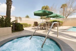 a hot tub with an umbrella and a table and chairs at Hilton Garden Inn San Jose/Milpitas in Milpitas