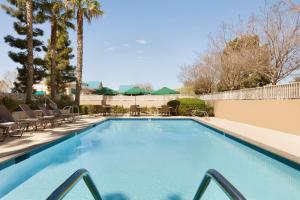 una piscina con mesas, sillas y palmeras en Hilton Garden Inn San Jose/Milpitas, en Milpitas