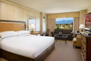 サンタクララにあるヒルトン サンタクララのベッドルーム(大型ベッド1台付)、リビングルームが備わります。