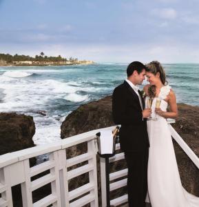 a bride and groom standing next to the ocean at The Condado Plaza Hilton in San Juan