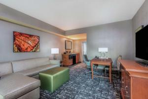 a living room with a couch and a tv and a desk at Embassy Suites by Hilton Saint Louis Saint Charles in St. Charles