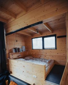 Cama en una cabaña de madera con ventana en Tiny Dream House, en Arnhem