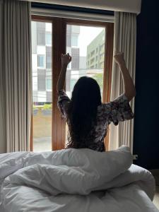 uma mulher sentada numa cama olhando pela janela em Neo Hotel Boutique em Lima