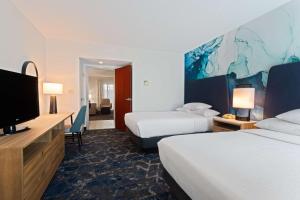 a hotel room with two beds and a flat screen tv at Embassy Suites by Hilton Tampa USF Near Busch Gardens in Tampa