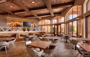 un restaurante con mesas y sillas y TV de pantalla plana en Embassy Suites Tucson - Paloma Village, en Tucson