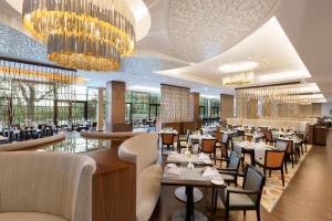 a restaurant with tables and chairs and chandeliers at DoubleTree by Hilton Hotel & Conference Centre Warsaw in Warsaw