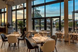 a restaurant with tables and chairs and large windows at Hilton Evian Les Bains in &Eacute;vian-les-Bains
