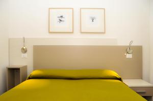 - une chambre avec un lit jaune et deux photos sur le mur dans l'établissement Hotel Da Mario, à Caorle