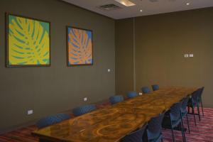 a long table in a room with chairs and paintings at Hampton By Hilton Valledupar in Valledupar
