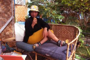 una mujer sentada en una silla comiendo un plátano en Hostel Posada de Gallo, en Arica