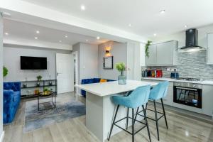 a kitchen and living room with a white counter and blue chairs at Free Parking 5 Minutes from City Centre in Manchester
