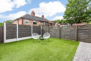 a backyard with two chairs and a fence at Free Parking 5 Minutes from City Centre in Manchester