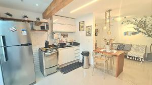 a kitchen with a stainless steel refrigerator and a table at Apto Aconchegante em Búzios - Condomínio Talhamar in Búzios