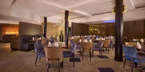 a dining room with tables and blue chairs at DoubleTree by Hilton Woking in Woking