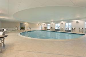 una grande piscina in una grande sala con tavoli e sedie di Hampton Inn & Suites Rosemont Chicago O'Hare a Rosemont