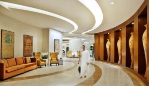 a man walking down a hallway in a hotel lobby at Conrad Makkah in Makkah