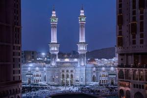 Conrad Makkah في مكة المكرمة: مبنى فيه برجين طويلين في مدينة في الليل