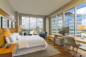a hotel room with a bed and a desk with a television at The Westin at The Woodlands in The Woodlands