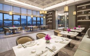 um restaurante com mesas e cadeiras brancas e janelas em DoubleTree by Hilton Hotel Shenzhen Longhua em Shenzhen