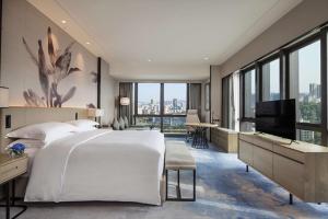 um quarto com uma cama grande e uma televisão de ecrã plano em DoubleTree by Hilton Hotel Shenzhen Longhua em Shenzhen