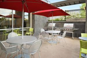 un patio con mesas, sillas y sombrillas rojas en Home2 Suites by Hilton Roseville Minneapolis, en Roseville