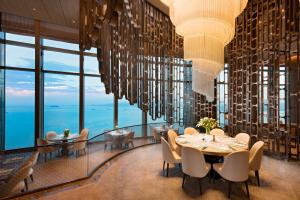 una sala da pranzo con lampadari pendenti, tavolo e sedie di Conrad Xiamen-Free Mini Bar a Xiamen