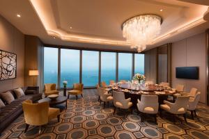 una sala da pranzo con tavolo, sedie e lampadario pendente di Conrad Xiamen-Free Mini Bar a Xiamen