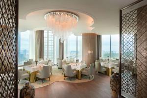 a dining room with tables and chairs and a chandelier at Conrad Xiamen-Free Mini Bar in Xiamen