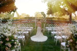 una mujer con un vestido de novia parada frente a un pasillo con sillas en The Inverness Denver, a Hilton Golf & Spa Resort en Englewood